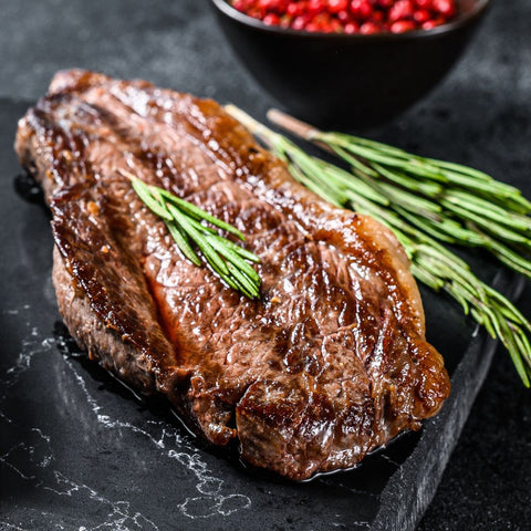 Älgryggbiff från svenskt älgkött på svart stenplatta med rosmarinkvist