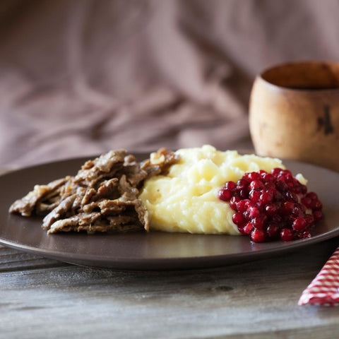 Renskav av högrev på svart tallrik med lingonsylt och potatismos