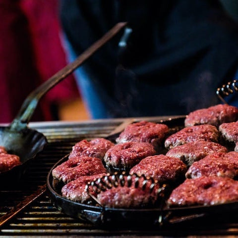 Älgfärs som steks i panna till älgburgare över en grill